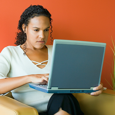 Illustrasjonsfoto: Ung kvinne sitter i lenestol og bruker bærbar PC