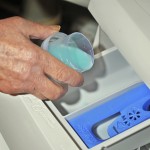 Hands of an elderly woman poured the powder in the cell washing machine