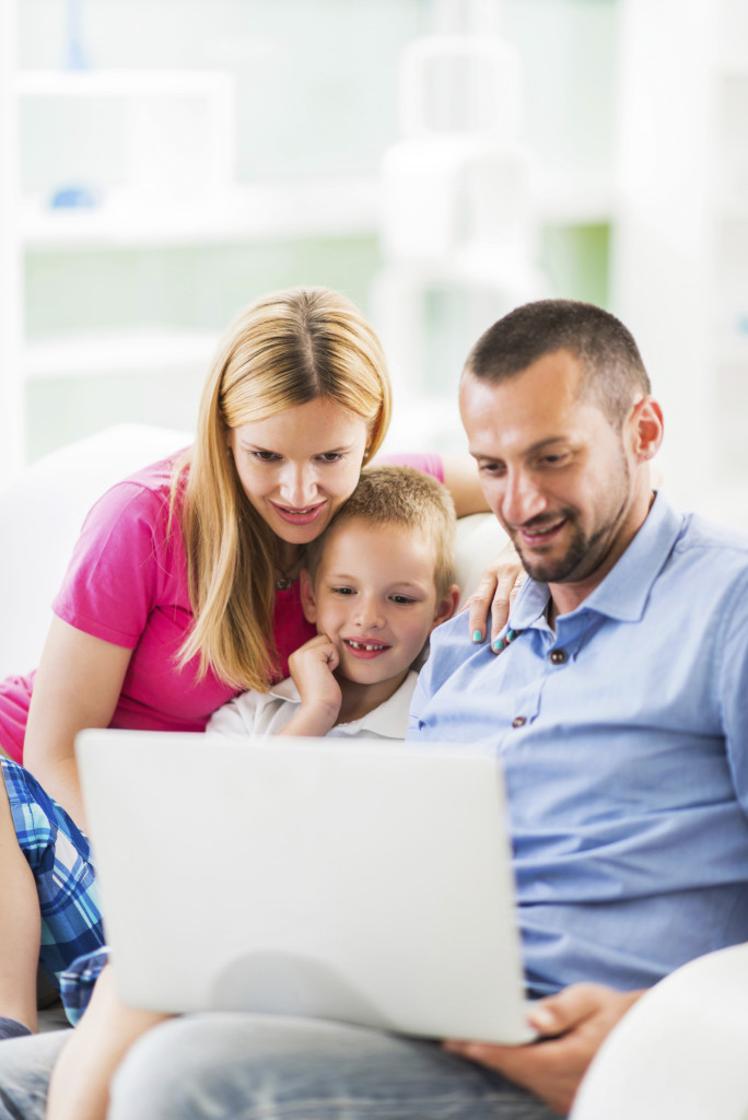 Happy mid adult parents teaching their son how to use a computer.