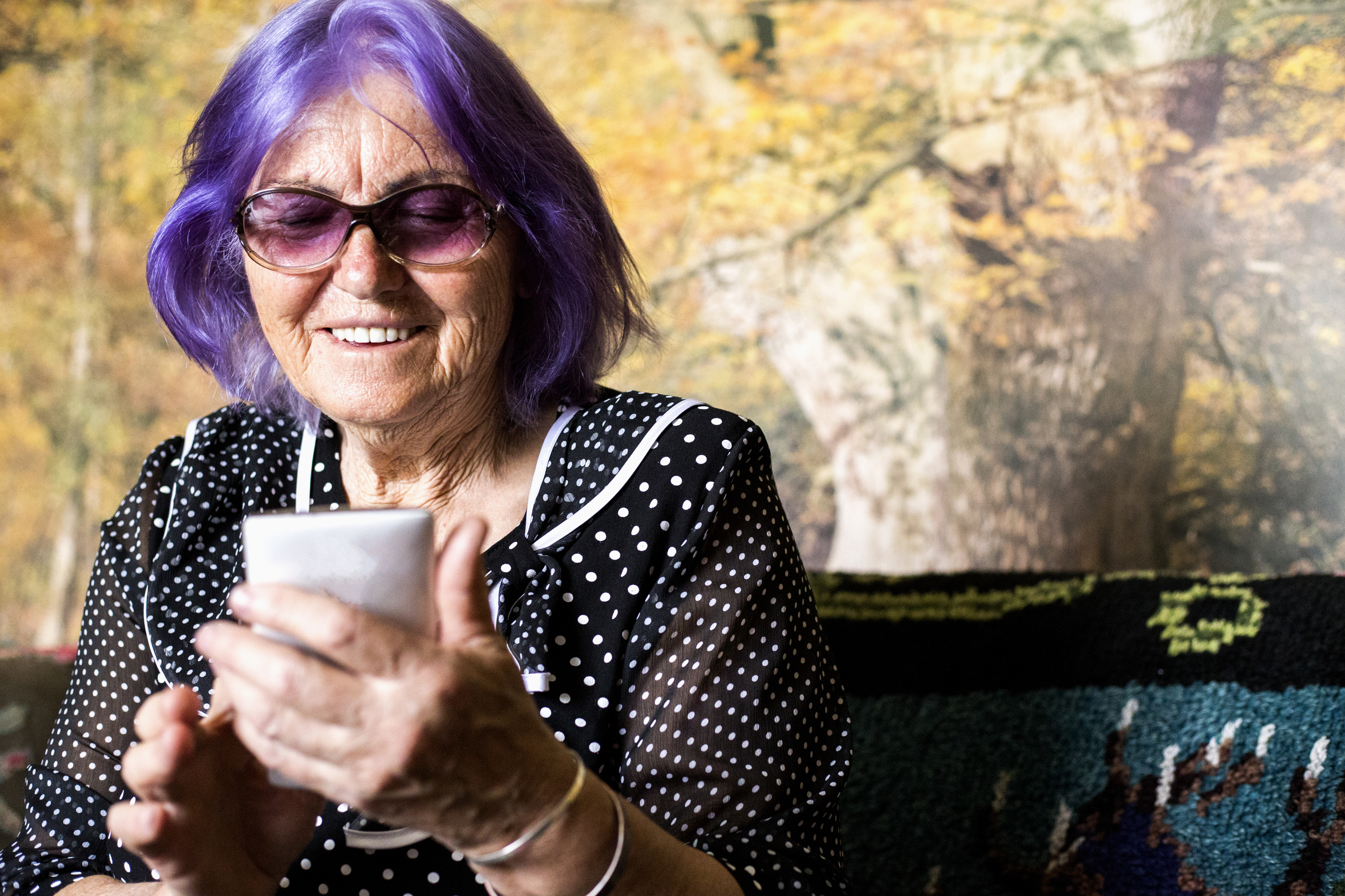 Eldre dame med violett hår smarttelefon i hånden.